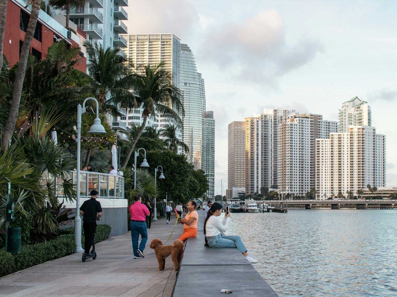 - Downtown Miami People walking on the Downtown Miami baywalk with towers across the water