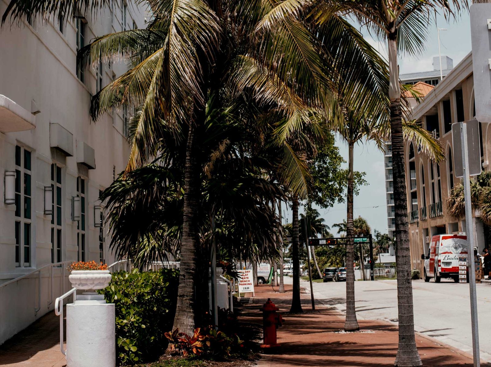 A shaded sidewalk and parked cars beside a white building, Fort Lauderdale