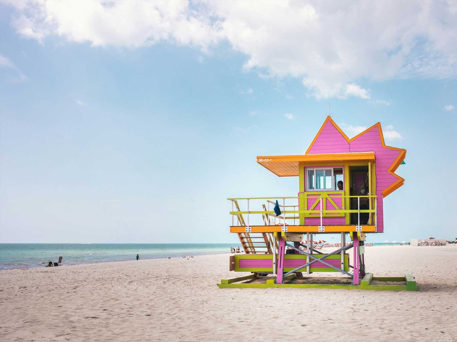 A pink and yellow Art Deco lifeguard tower on the sand at Miami Beach