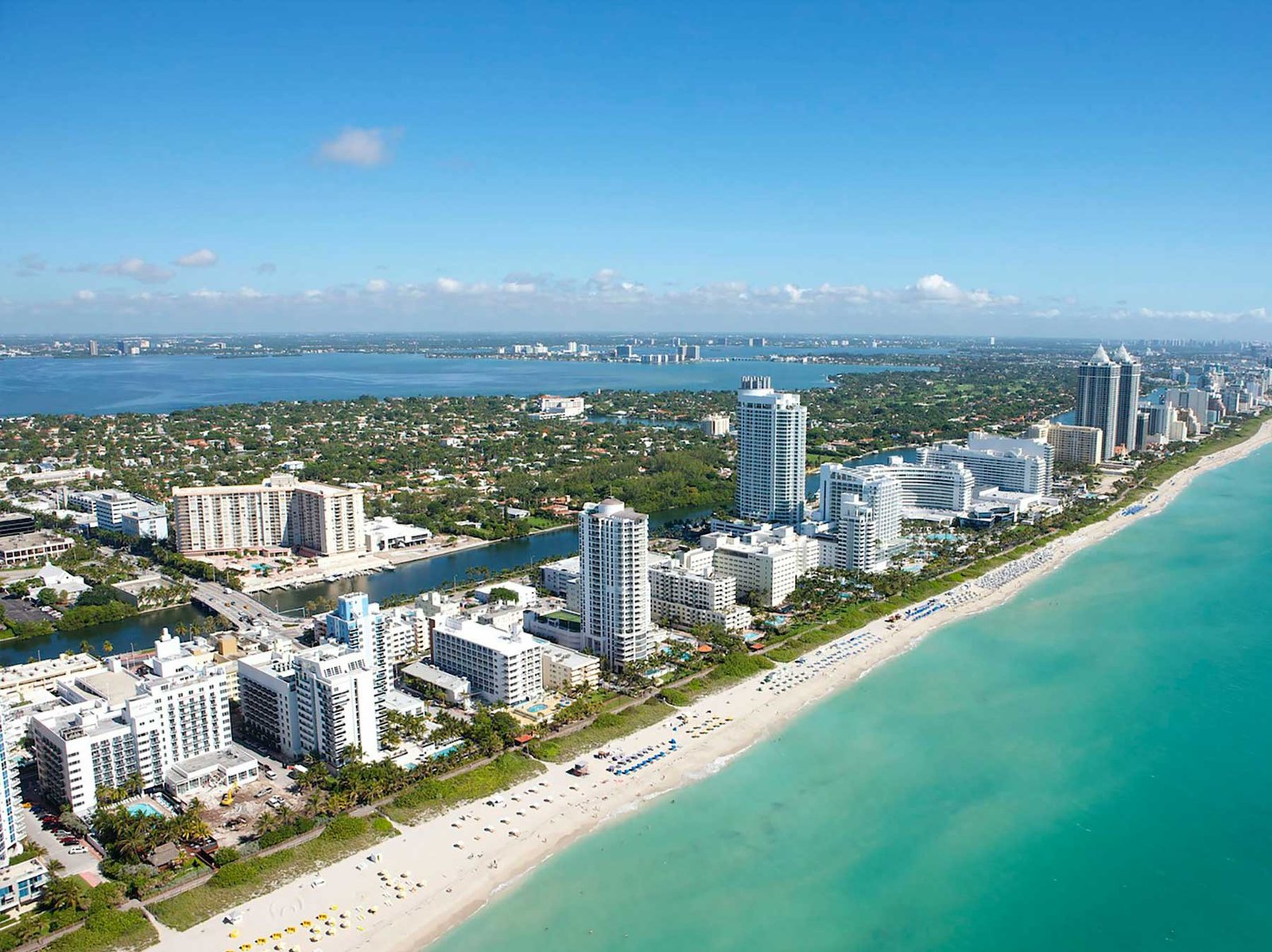 Aerial along the Miami Beach oceanfront showing low blocks giving way to taller towers