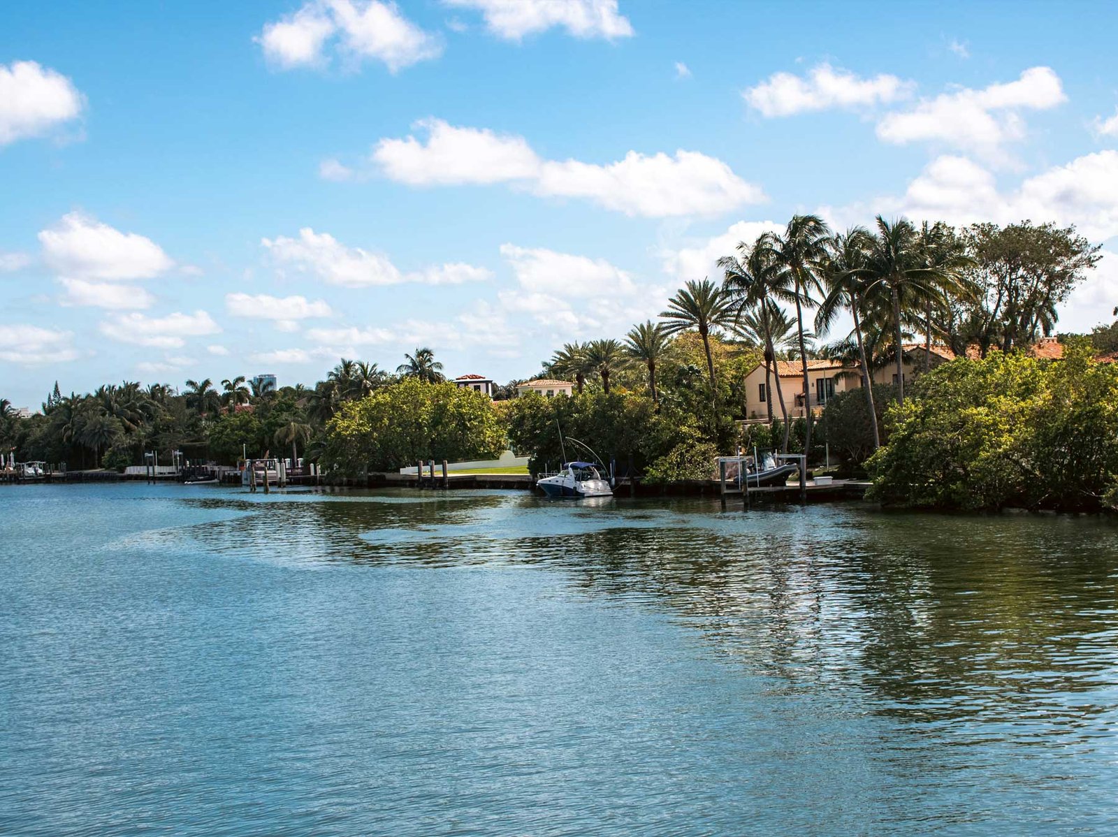 A tree-lined Miami residential canal with waterfront houses and private docks
