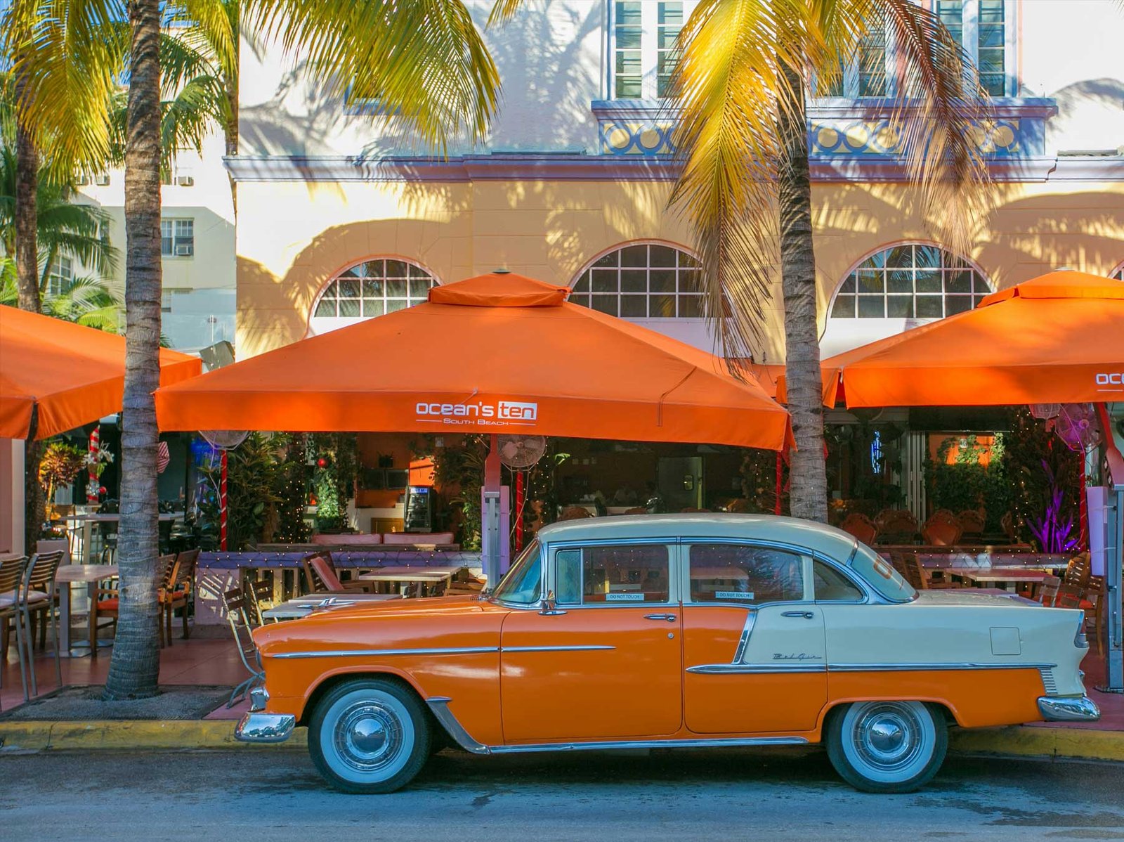 Classic car parked outside an Art Deco cafe on Ocean Drive, South Beach