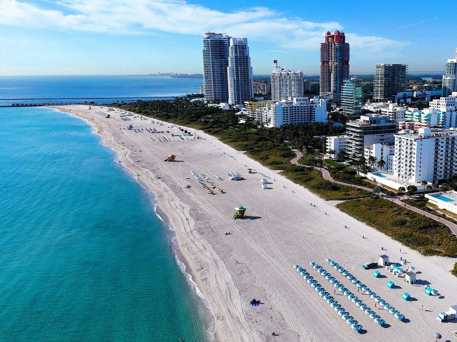 Aerial of the South Beach shoreline — sand, loungers and the low Art Deco building line behind