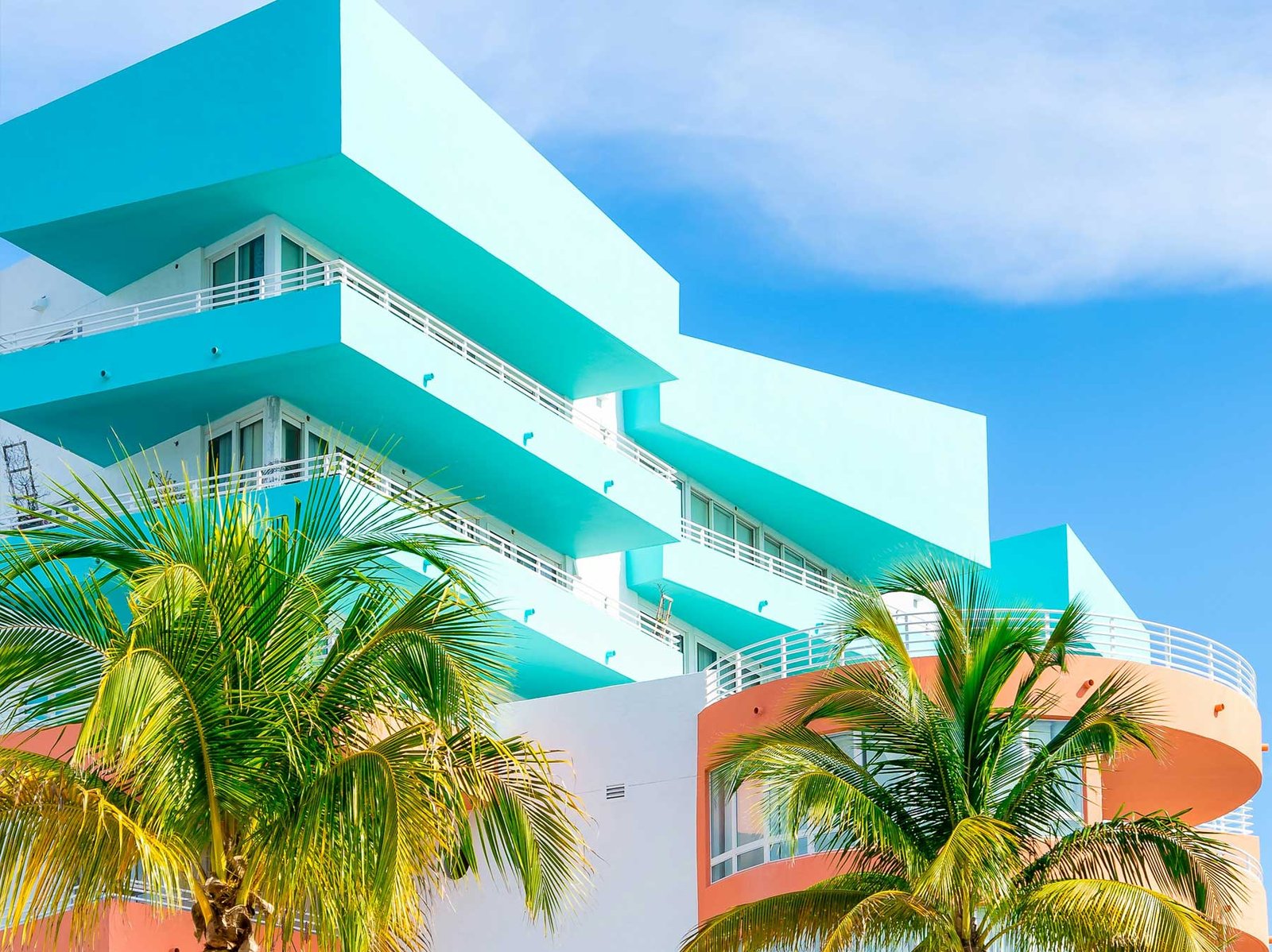 Pastel Art Deco building with rounded balconies and palms, South Beach
