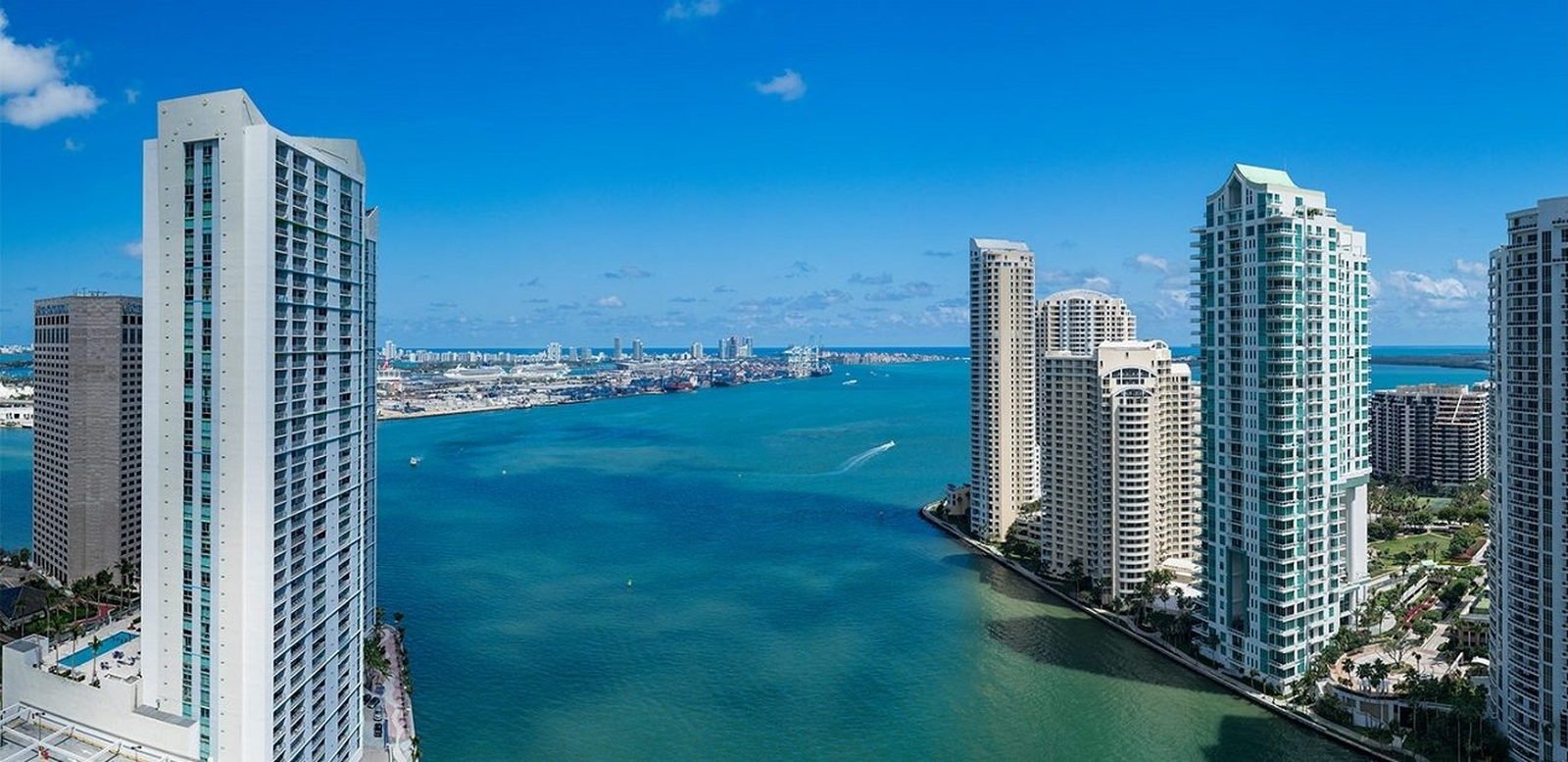 Aerial across the water to Brickell Key, with the Port of Miami and its cranes in the distance