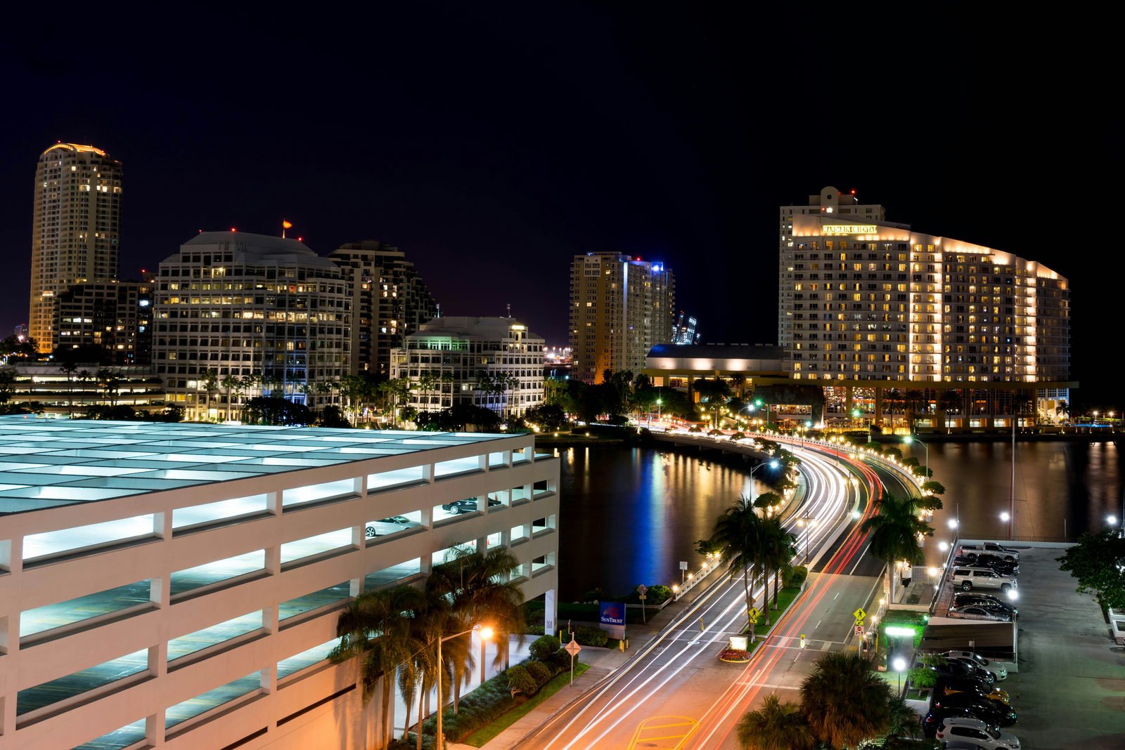 Brickell Key Drive at night, headlight trails along the causeway with the island's towers lit behind